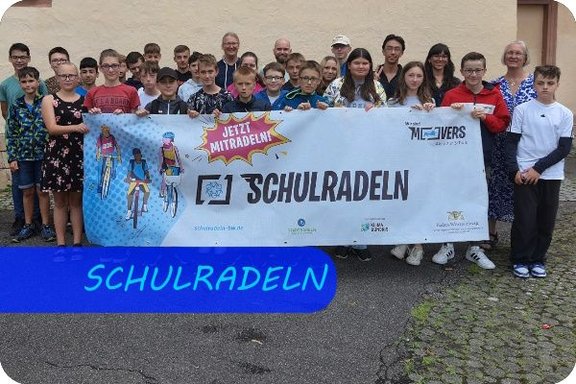 Bild mit der Überschrift "SCHULRADELN", eine Gruppe von Schüler:innen und Lehrer:innen hat sich zum Foto aufgestellt und hält ein großes Banner mit der Aufschrift "SCHULRADELN" vor sich. 