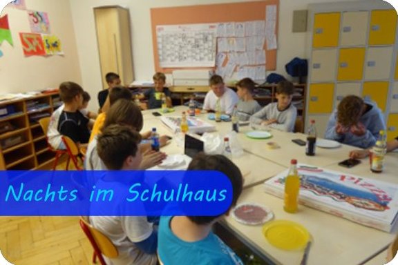 Bild mit der Überschrift "Nachts im Schulhaus", Schüler sitzen um zusammengestellte Tische zusammen, auf denen ein Pizzakarton steht