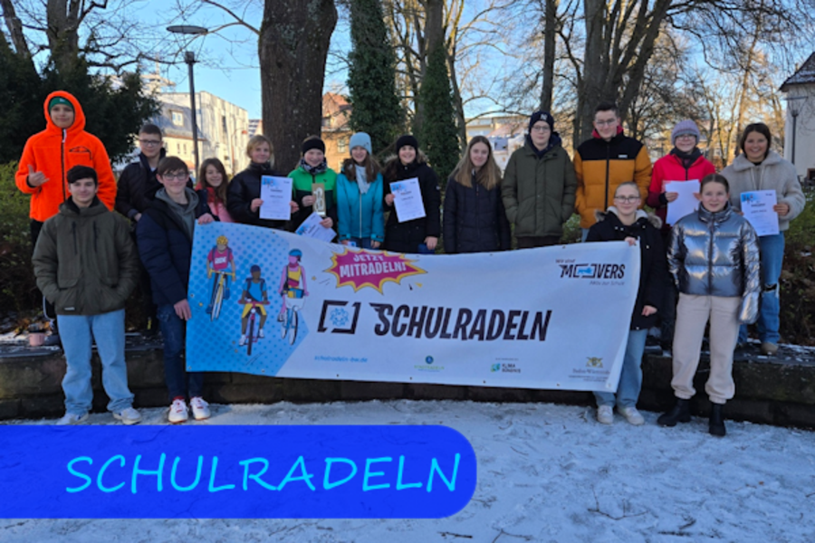 Mehrere Schülerinnen und Schüler stehen als Gruppe hinter einem Banner, auf dem SCHULRADELN steht. 