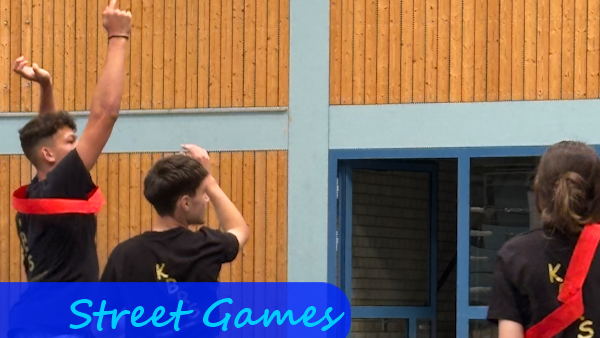 In einer Halle sieht man drei Personen eines Teams mit dunklem Trikot. Der Junge ganz links hat gerade einen Ball geworfen, während die anderen beiden diesem hinterherschauen.