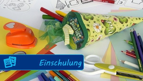 Auf einem Schreibtisch liegen Schulsachen wie Schere und Stifte und eine kleine Zuckertüte.