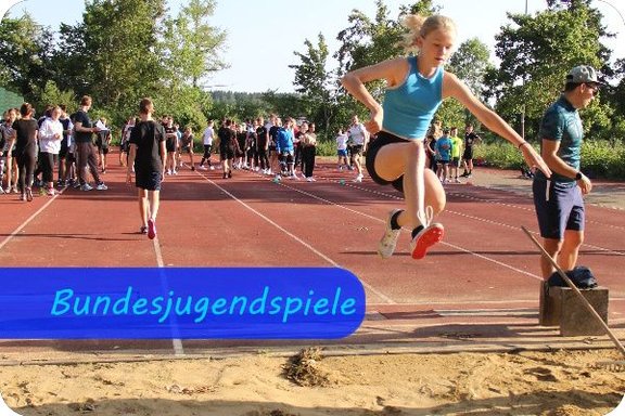 Bild mit der Überschrift "Bundesjugendspiele" auf dem eine Schülerin beim Weitsprung vom Brett abgesprungen ist und in der Luft die Beine nach vorne reißt.