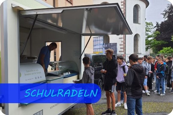 Im Vordergrund steht auf der linken Seite ein Eiswagen. Ein Mann gibt darin gerade eine Eiskugel in eine Waffel. Vor dem Wagen steht ein Junge, der auf das Eis wartet. Dahinter befinden sich eine lange Schlange Kinder.
