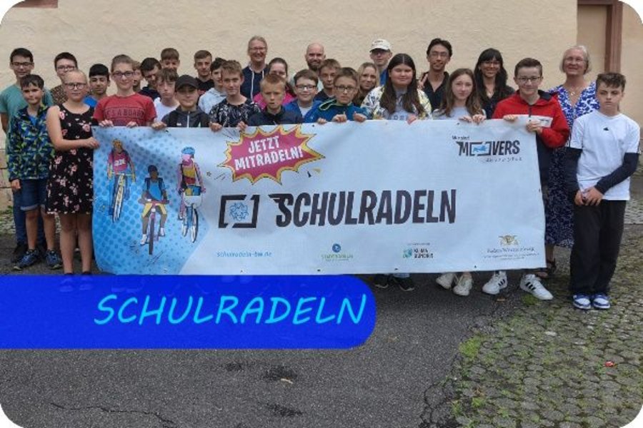 Bild mit der Überschrift "SCHULRADELN", eine Gruppe von Schüler:innen und Lehrer:innen hat sich zum Foto aufgestellt und hält ein großes Banner mit der Aufschrift "SCHULRADELN" vor sich.