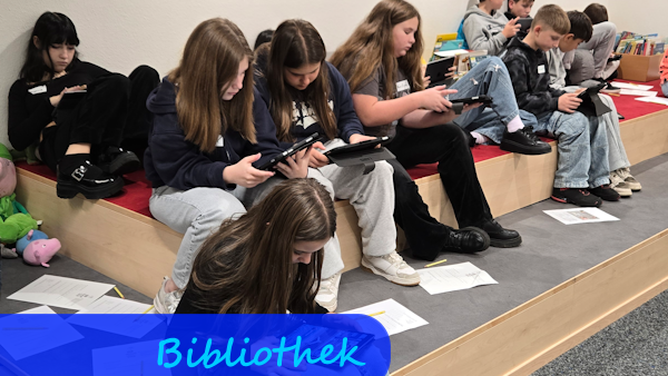 Auf Treppenstufen, die zum Sitzen mit Teppich belegt sind, sitzen Mädchen und Jungen mit Tablets in der Hand.