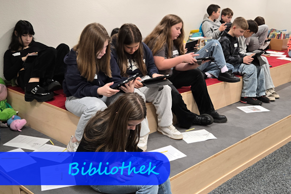 Auf Treppenstufen, die zum Sitzen mit Teppich belegt sind, sitzen Mädchen und Jungen mit Tablets in der Hand.