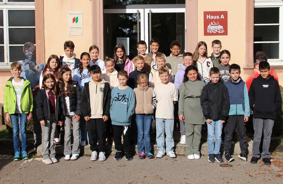 Vor dem Eingang der Schule hat sich eine fünfte Klasse zum Gruppenfoto aufgestellt.