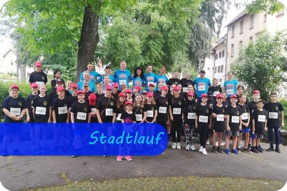 Bild mit der Überschrift "Stadtlauf". Alle Teilnehmer:innen am Stadtlauf der KBRS sind darauf zu sehen. Im Vordergrund die Schüler:innen mit schwarzen T-Shirts, im Hintergrund die Lehrkräfte mit hellblauen T-Shirts.