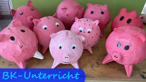 Auf einem Tische stehen mehrere rosa Sparschweine, die aus Papiermaché hergestellt wurden.